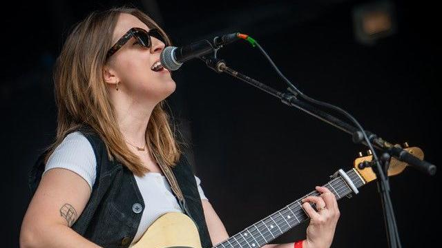 Charlotte Carpenter playing a guitar and singing