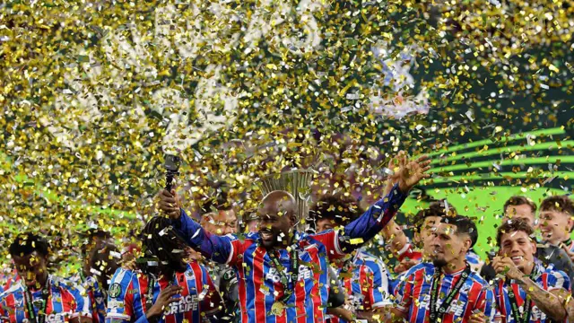 Mateta holds his hands aloft as ticker tape rains down on Crystal Palece players.