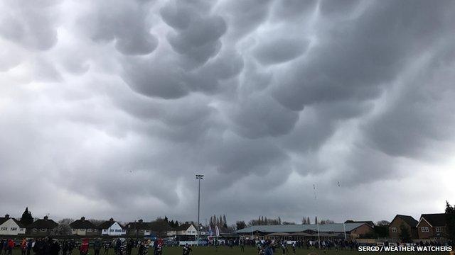 A sports ground with dark udder-like clouds in the sky