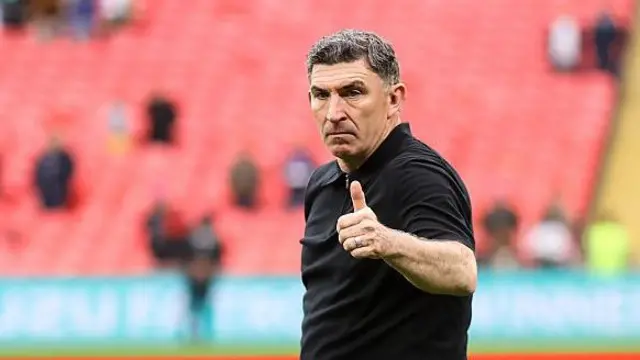 Southend head coach Kevin Maher in a black t-shirt gives a thumbs up to supporters