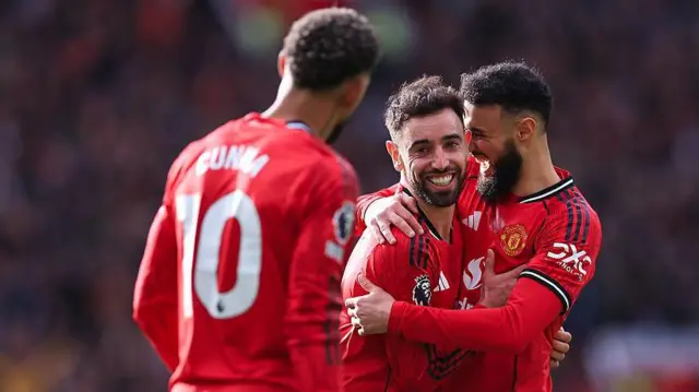 Bruno Fernandes of Manchester United celebrates with Noussair Mazraoui and Matheus Cunha