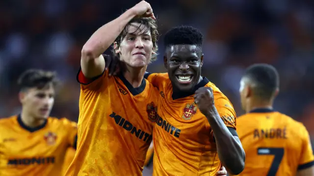 Fer Lopez and Marshall Munetsi, wearing Wolves' Old Gold home shirts, celebrate the first goal against Blackburn together by putting their arms around each other 