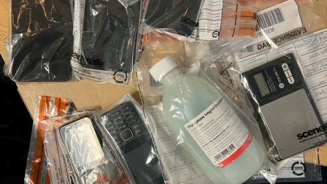 Seized phones and drug equipment in plastic evidence bags