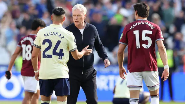 David Moyes walks on the pitch at West Ham. He shakes hands with Alcaraz as Mavropanos looks on
