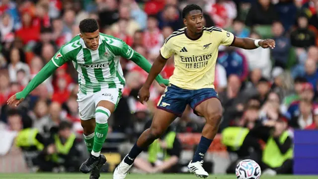 Myles Lewis-Skelly of Arsenal is put under pressure by Nelson Deossa of Real Betis