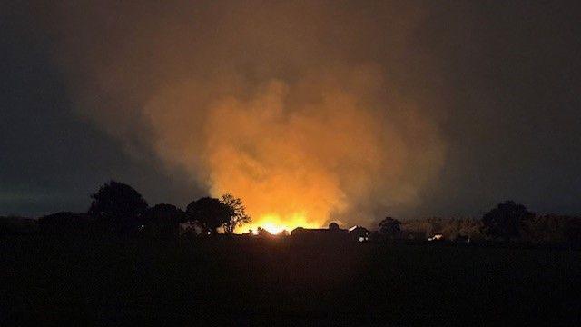 An orange blaze in the distance with billowing clouds of smoke