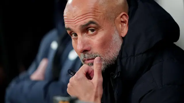 Pep Guardiola sits in the dugout