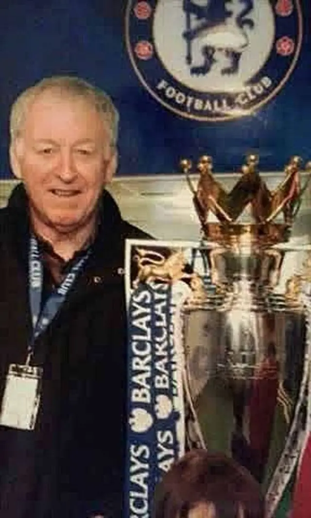 An image of a man stood next to the Barclays Premier League trophy with a Chelsea crest behind him