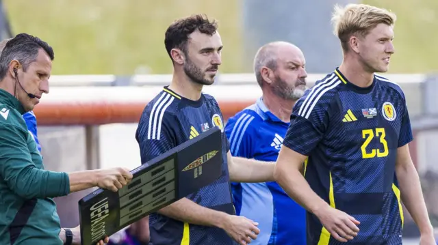 Scotland's Andy Irving (C) and Josh Doig prepare to be substituted on during an International Friendly match between Liechtenstein and Scotland at Rheinpark Stadion