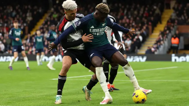 Bukayo Saka and Antonee Robinson challenge for the ball