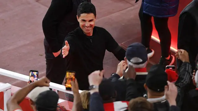 Mikel Arteta interacts with fans as he walks down the tunnel
