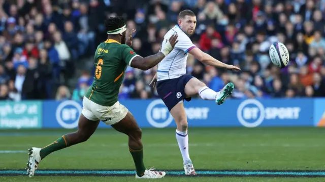 Finn Russell kicks past South Africa captain Siya Kolisi in 2021