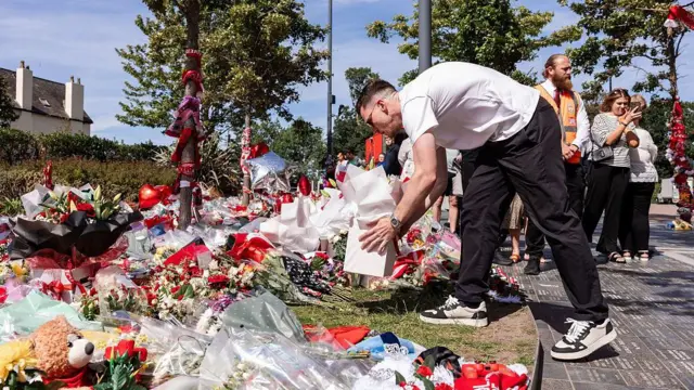 Andy Robertson places flowers on the ground outside Anfield