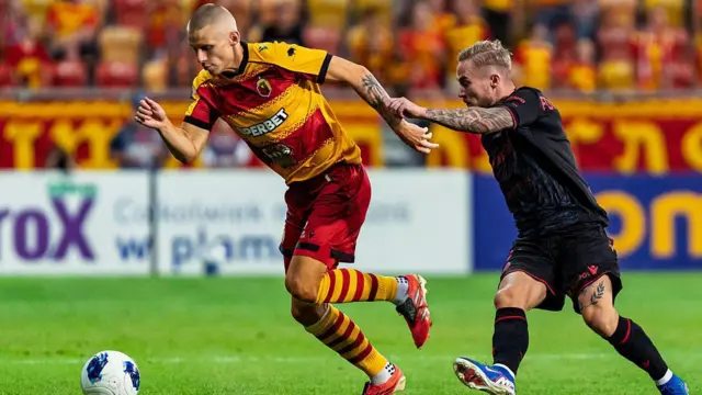 Norbert Wojtuszek of Jagiellonia Bialystok (L) is chased by Mariusz Fornalczyk of Widzew Lodz (R)