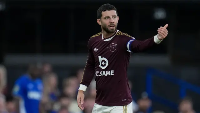 Conor Chaplin shouts instructions out and points with his left arm during a game for Leicester City. He is wearing a claret coloured away shirt.