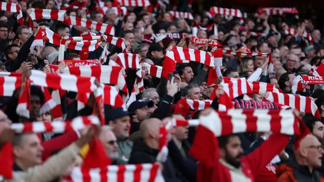 Arsenal fans hold up scarves during match