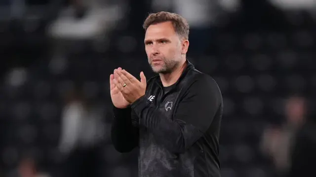 John Eustace walks on the pitch and claps his hands