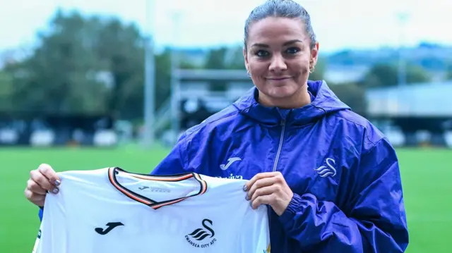 Nia Jones holds up a Swansea shirt