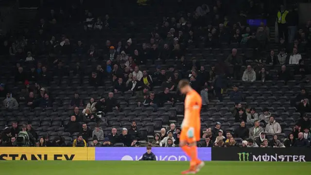 Vicario in the foreground in front of a sparsely populated Tottenham Hotspur Stadium