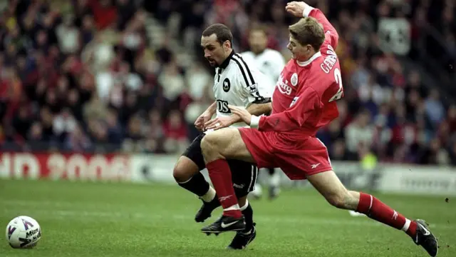 Steven Gerrard, wearing Liverpool's all red home kit, lunges into a sliding tackle on Derby's Francesco Baiano during a Premier League game at Pride Park in March 1999