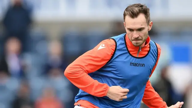 Ryan Hedges, wearing an orange zip-up jacket and a blue vest, warms up for Blackburn Rovers before their game against Southampton in April