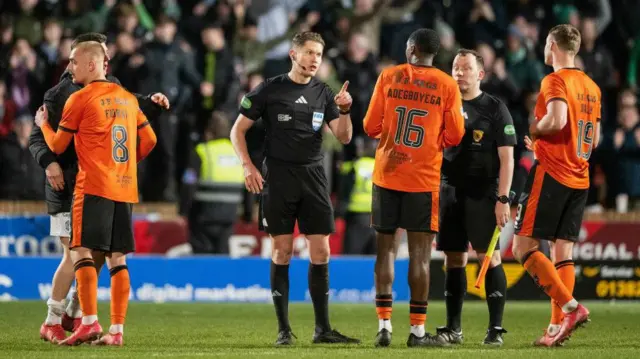 Referee David Dickinson speaks to Dundee United defender Emmanuel Adegboyega.