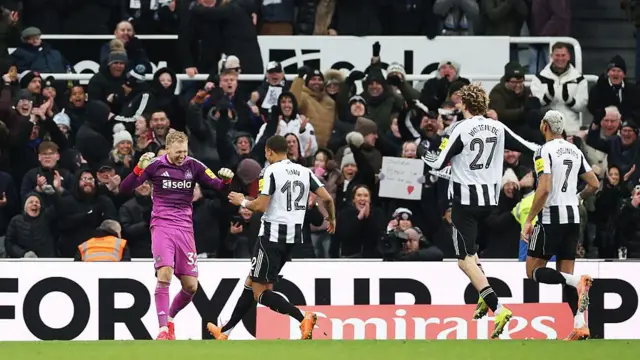 Malick Thiaw of Newcastle United and teammate Nick Woltemade celebrate with Aaron Ramsdale
