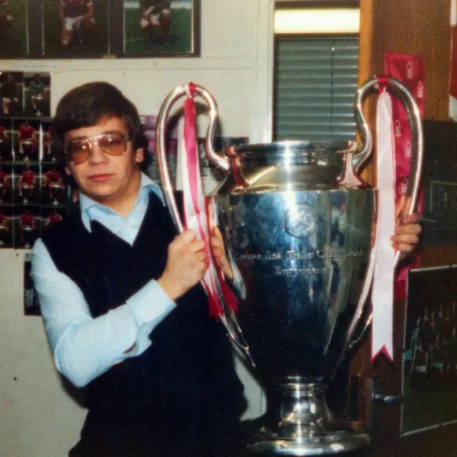 A man in dark glasses has his hands on the European Cup trophy