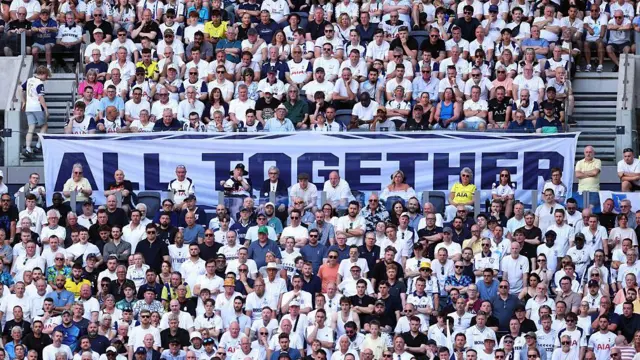 Tottenham fans in Tottenham Hotspur Stadium. A sign among them reads 'all together'
