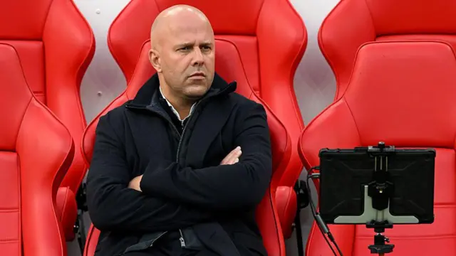 Arne Slot sitting alone in the Anfield dugout