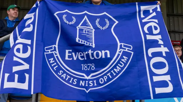 An Everton fan holding up a flag