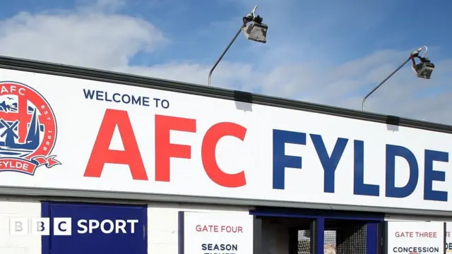 Close-up image of AFC Fylde logo in red and blue lettering.