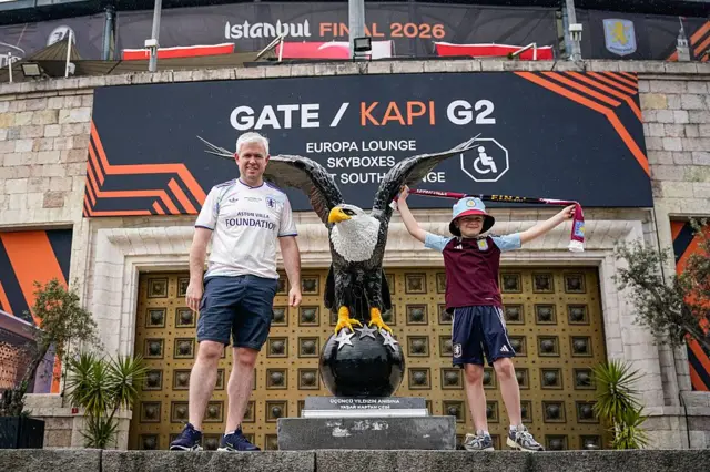 Aston Villa fans pose near the eagle statue in front of the Besiktas Park prior to the UEFA Europa League Final 2026 match between SC Freiburg and Aston Villa FC at Besiktas Park 