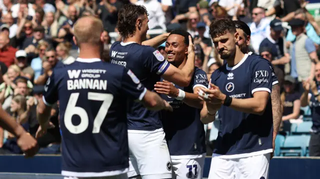 Femi Azeez receiving congratulations from his Millwall team-mates after scoring against Oxford United