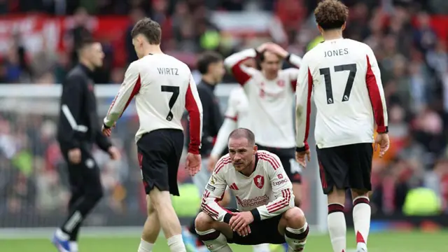 Liverpool players including Mac Allister look dejected. Mac Allister crouches down after a game looking sad.