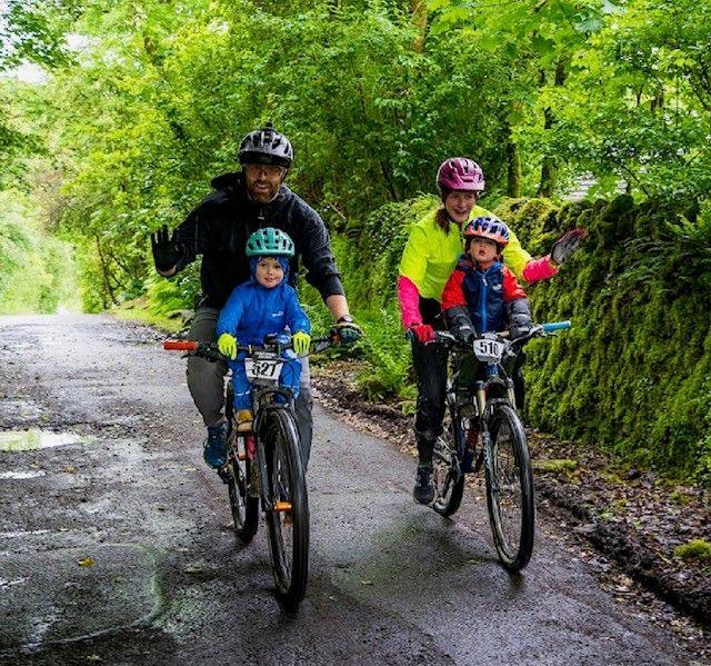 A family of four cycling in the woods in Aberfoyle