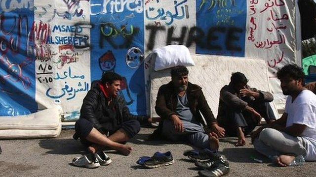 migrant sit outside large tent