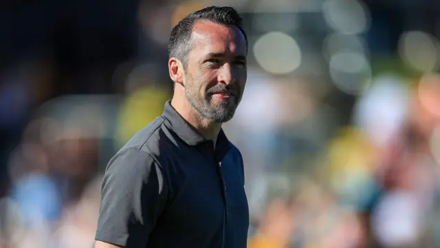 Newport County manager Christian Fuchs in a short sleeved grey shirt smiles during his sides dramatic 3-2 win against Oldham.