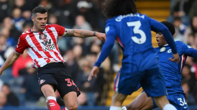 Granit Xhaka of Sunderland has a shot on goal blocked by Josh Acheampong of Chelsea during the Premier League match between Chelsea and Sunderland at Stamford Bridge on October 25 2025