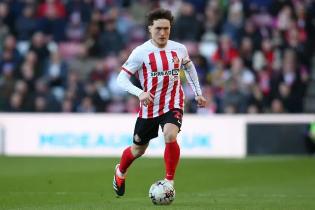 Callum Styles dribbling with a football in Sunderland's home kit