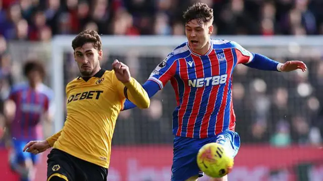 Santiago Bueno of Wolves passes the ball while under pressure from Jorgen Strand Larsen of Crystal Palace