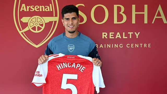 Piero Hincapie holding up Arsenal number five shirt after signing