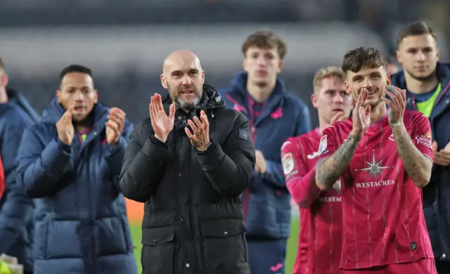 Swansea players and staff salute the travelling fans after victory at Hull