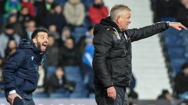 Chris Wilder on the touchline, pointing. In the background is Carlos Corberan who is shouting instructions.