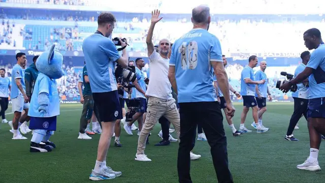 Manchester City manager Pep Guardiola is surrounded as he waves farewell.