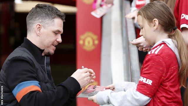 Manchester United boss Marc Skinner signs an autograph for a young fan at Old Trafford before the Women's Super League match with Everton