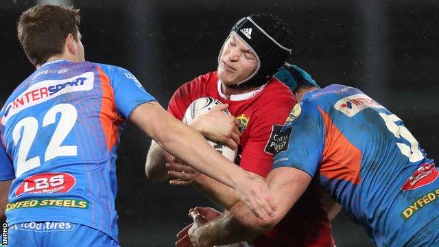 Munster's Tyler Bleyendaal is halted by a tackle from Scarlets replacement Aled Thomas