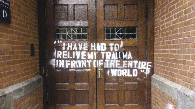 Photo of graffiti on a door that reads "I have had to relive my trauma in front of the entire world"