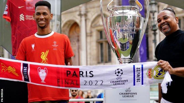 Fans stand next to the Champions League trophy in Paris