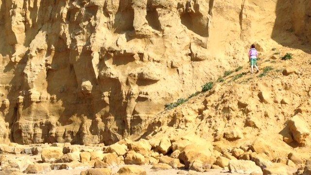 A child climbing on a collapsed section of cliff